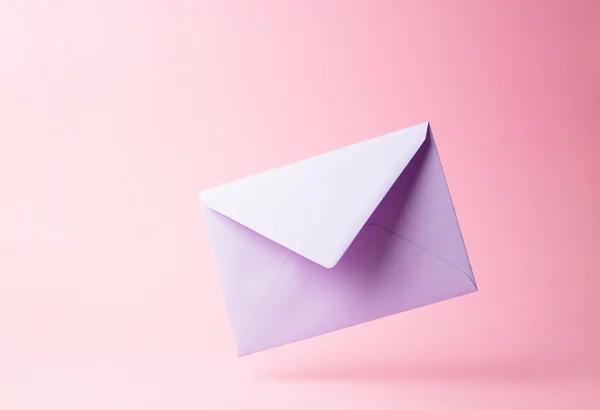 Фиолетовый конверт упал на розовый — стоковое фото