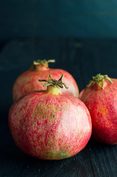 Pomegranates over dark wooden — Stock Photo, Image