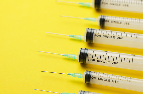 Детали шприцев над ярко-желтым

