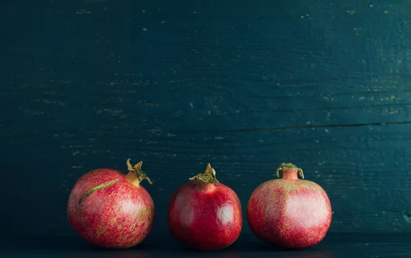 Pomegranates over dark wooden — Stock Photo, Image