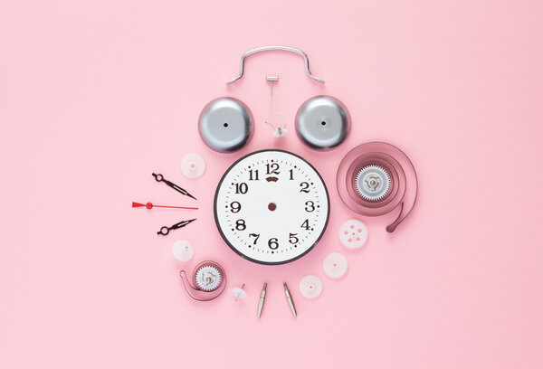 Clock components organized over pink 