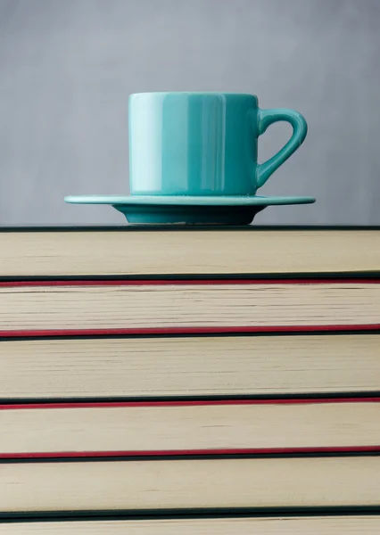 Blauwe koffiekopje op stapel boeken — Stockfoto