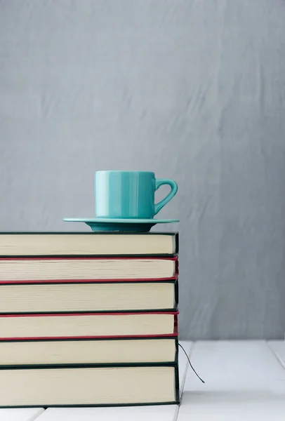 Blauwe koffiekopje op stapel boeken — Stockfoto