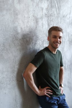 Happy, handsome man on a concrete wall background