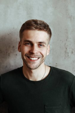 Happy, handsome man on a concrete wall background