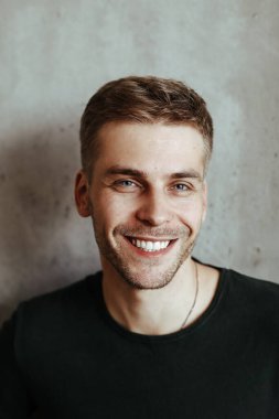 Happy, handsome man on a concrete wall background