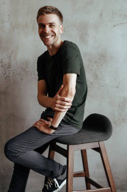 Happy, handsome man on a concrete wall background