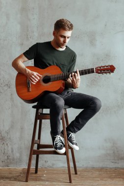 Performansı sırasında gitar çalan yakışıklı bir adam.