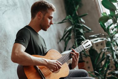 Performansı sırasında gitar çalan yakışıklı bir adam.
