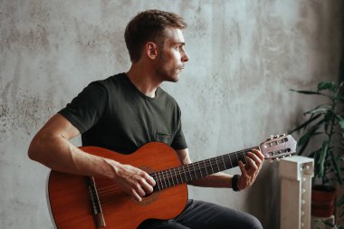 Performansı sırasında gitar çalan yakışıklı bir adam.