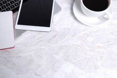 Tahta bir masada beyaz bir fincan kahve ve dizüstü bilgisayar. en üstteki görünüm.