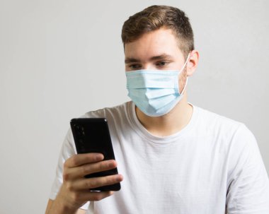 Salgın sırasında akıllı telefon kullanan yüz maskeli bir iş adamı.