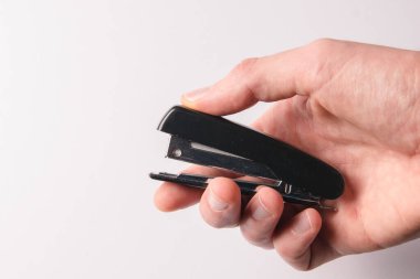 Beyaz arka planda siyah bir zımba tutan el. El işi, kağıt, ofis kavramı.