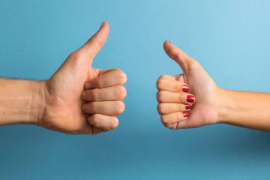 Kadın ve erkek elleri mavi arka planda olumlu jestler yapıyor..