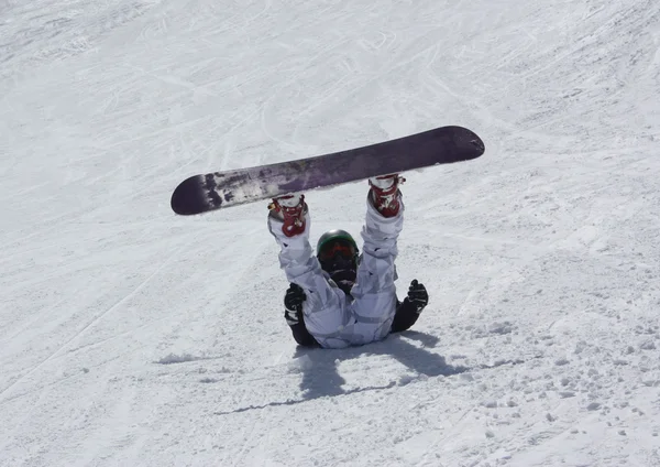 Mladý snowboardista žena leží na sjezdovce a vzhůru nohama. — Stock fotografie