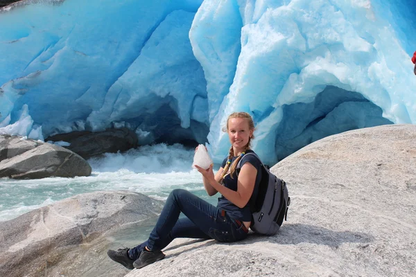 Jeune femme sur le Nigardsbreen, assise avec un morceau de glace. Glacier en Norvège . — Photo