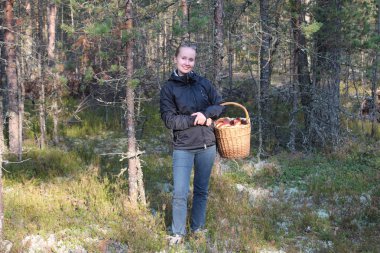 Young woman with a basket of cepes mushrooms in the forest clipart
