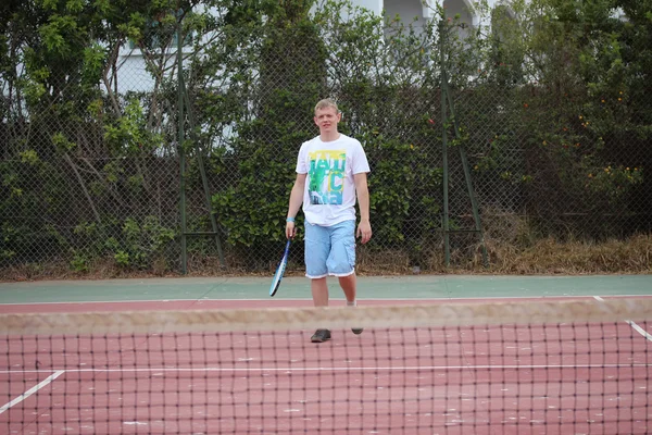 Mladý muž hrát tenis venkovní. — Stock fotografie