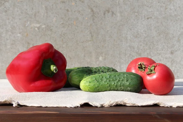 Ingredientes para a salada de legumes: uma pimenta, três pepinos e dois tomates . — Fotografia de Stock