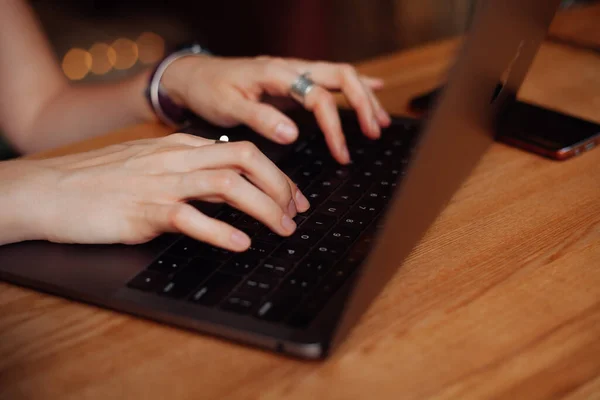 Girl\'s fingers are typing a letter on a black laptop