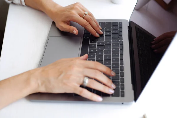 girl\'s fingers are typing on a black laptop keyboard
