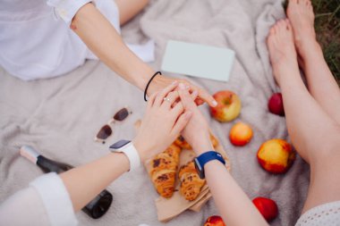 Üç kız arkadaş bir piknikte el ele tutuşuyorlar.