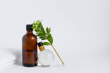 Büyük ve küçük kahverengi yağ kavanozu ve beyaz izole arkaplanda yeşil bir filiz bulunan cam bir top. Sıfır atık cam kap. Güzellik, cilt bakımı. Spa ürünleri