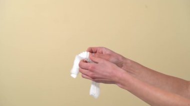 Kadın elleri açık ve bej izole bir arka planda lastik bantlı, şeffaf bir saç şapkası gösteriyor..