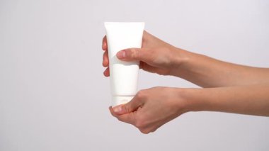 Kadın eller beyaz bir kozmetik model tüp açıyor ve beyaz arka planda avuç içine krem sıkıyor. Gösteriş için ideal nemlendirici, besleyici cilt bakımı, ya da güzellik ürünü kullanımı