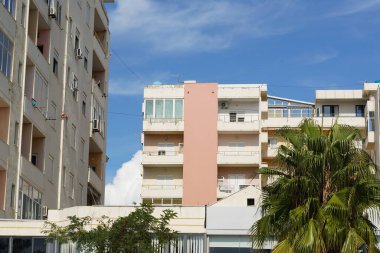 Kutu balkonları ve perdede görünen klima üniteleri olan küçük bir bina. Kiralık daireler, emlak piyasaları, dijital göçebeler ve yabancı emlak yatırımları için harika..