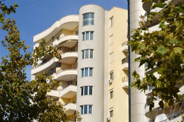 Güneşli, sarı bir apartman bloğu, balkonları ve modern eserleri var. Emlak yatırımcıları, mobilyalı kiralama piyasaları, şehir yaşam tarzı arayıcıları ve kentsel gayrimenkul fırsatları için elverişli.