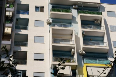 Fonksiyonel balkonları ve minimalist mimarisi olan yumuşak mavi çok katlı bir apartman. Arnavutluk 'ta gayrimenkul aramaları, kiralık evler, belediye daireleri ve yabancı alıcılar için elverişli.