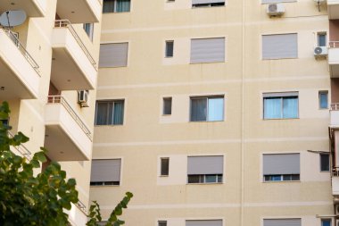 Arnavutluk 'un bir şehrinde çağdaş Akdeniz tarzı bir apartman, ön cephe, büyük pencereler. Uygun kira listeleri, emlak alımları, taşınma desteği, tatiller ve ajans portföyleri.