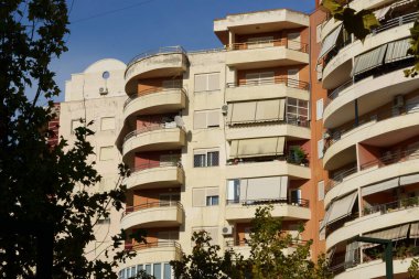 Minimum dekorasyonu ve geniş terasları olan Akdeniz 'den esinlenilmiş Arnavut binası. Emlak kiralama, emlak satın alma, taşınma yardımı ve tatil konaklama için elverişli.