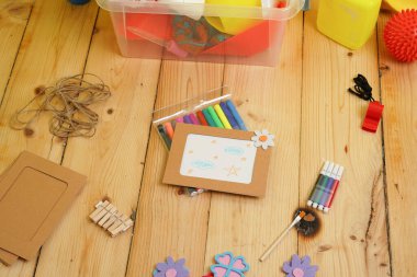 Renkli çocuk sanat ve el sanatları malzemelerinin olduğu bir daire. İşaretler, el yapımı bir çerçeve ve diğer yaratıcı aletler açık ahşap bir zeminde. Oyuncu, eğitici ve DIY konsepti.