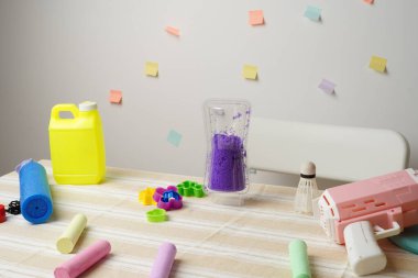 Masada renkli çocuk oyuncakları ve sanat malzemeleri var. Tebeşir, kinetik kum ve baloncuk tabancalı neşeli bir sahne. Parlak, pastel renkler ve yumuşak ışıklandırma yaratıcılığı ve çocukluk eğlencesini çağrıştırıyor.