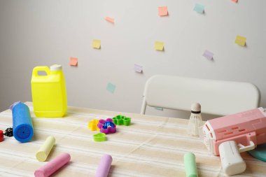 Çizgili bir masa örtüsü üzerinde çocuk oyuncaklarının neşeli bir sahnesi. Baloncuk tabancası, tebeşir ve kalıplar. Pastel renkler ve yumuşak ışık eğlenceli ve yaratıcı bir hava yaratıyor. Çocukluk kavramları için mükemmel.