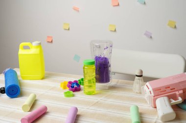 Çocukların yaz oyuncaklarının hayat enerjisi masada erzak üretiyor. Baloncuk tabancası, tebeşir, kalıp, çözüm. Neşeli pastel renkler parlak ışıklandırma eğlenceli, yaratıcı bir çocukluk havası yaratır..