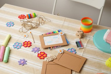 Bir çocuğun yaratıcı çalışma alanına yüksek açılı bir bakış açısı. Masa, bir DIY fotoğraf çerçevesi projesi için keçeli kalem, tebeşir ve keçeli çiçek gibi renkli sanat malzemeleriyle ve çeşitli oyuncaklarla dolu..