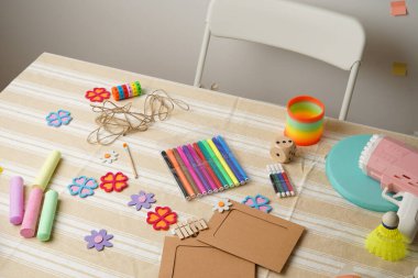 Kalem ve tebeşir gibi renkli çocuk sanat malzemeleriyle dolu dağınık bir masanın yüksek açılı görüntüsü artı çeşitli oyuncaklar ve el işi eşyalar. Yaratıcılık, oyun ve çocukluk gelişimi kavramı.