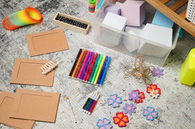 Çocukların yaratıcı oyun saatlerine tepeden tırnağa bakmak. Renkli kalemler, bloklar, oyuncaklar ve el sanatları malzemeleri bir halıya serilmiş, sanat projesi için hazırlar. Evde öğrenme, hayal gücü ve eğlenceyi çağrıştırıyor.