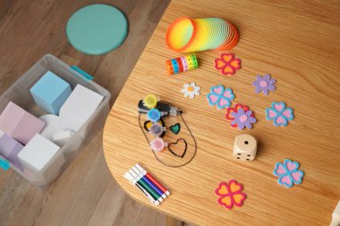Ahşap bir masada renkli çocukların resim malzemelerini ve eğitici oyuncakları yüksek açılı görüyor. İçinde gökkuşağı yayı, boya, bloklar ve işaretler var. Yaratıcılık, öğrenme ve çocukluk gelişimini çağrıştırır.