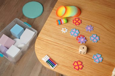 Renkli oyuncaklarla dolu bir çocuk oyun odası manzarası. Ahşap bir masada eğitim oyunları, bloklar ve sanat malzemeleri. Çocukluk gelişimi ve öğrenme için oyuncu, yaratıcı bir kavram.