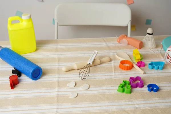 Renkli oyuncak koleksiyonu, pişirme aletleri ve çizgili masa örtüsü üzerindeki nesneler. Yaratıcı oyun, çocukluk aktiviteleri, kaos, dağınıklık ya da düzensizliği öneren parlak bir sahne.