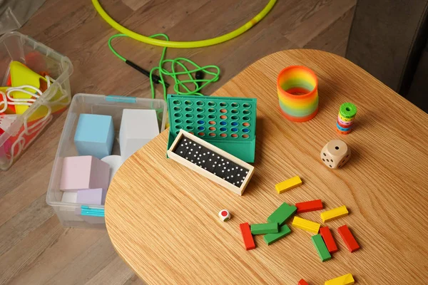 Tahta masaya saçılmış bloklar, dominolar ve masa oyunları gibi renkli çocukların oyuncaklarının yüksek açılı görüntüsü. Çocukluk ve kalkınma kavramları için oyuncu ve eğitici bir ortam.