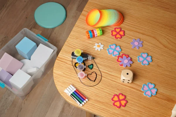 Ahşap bir masada renkli çocukların resim malzemelerini ve eğitici oyuncakları yüksek açılı görüyor. İçinde gökkuşağı yayı, boya, bloklar ve işaretler var. Yaratıcılık, öğrenme ve çocukluk gelişimini çağrıştırır.