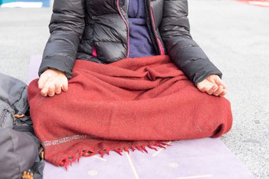 Yoga öğretmenleri İtalya 'nın Brescia kentindeki bir meydanda Covid-19' un abluka ve kısıtlamalarını protesto ediyorlar. Çapraz bacakların üzerinde dinlenen ellerin görüntüsü. İnsanlar meditasyon yapıyor..