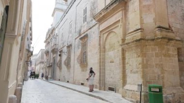 Mdina, Malta, insanlar tipik bir sokakta yürür.