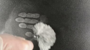 Parmak izleri, fırça siyah yüzeyde gizli el izleri oluşturur.