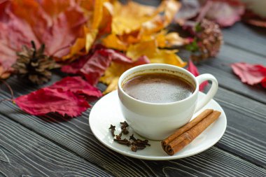 Baharatlı kahve, tarçın, karanfil ve kırmızı biber. Ahşap arka planda düşen sonbahar akçaağaç yaprakları.